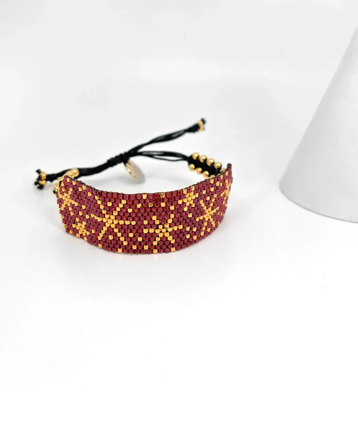 Pulsera artesanal de lujo Erika Valencia en tonos rojo y dorado con diseño detallado y cierre ajustable