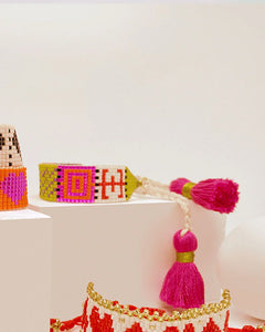 Pulsera artesanal colombiana de Erika Valencia con diseño colorido y detalles en hilo rosa y mostacillas