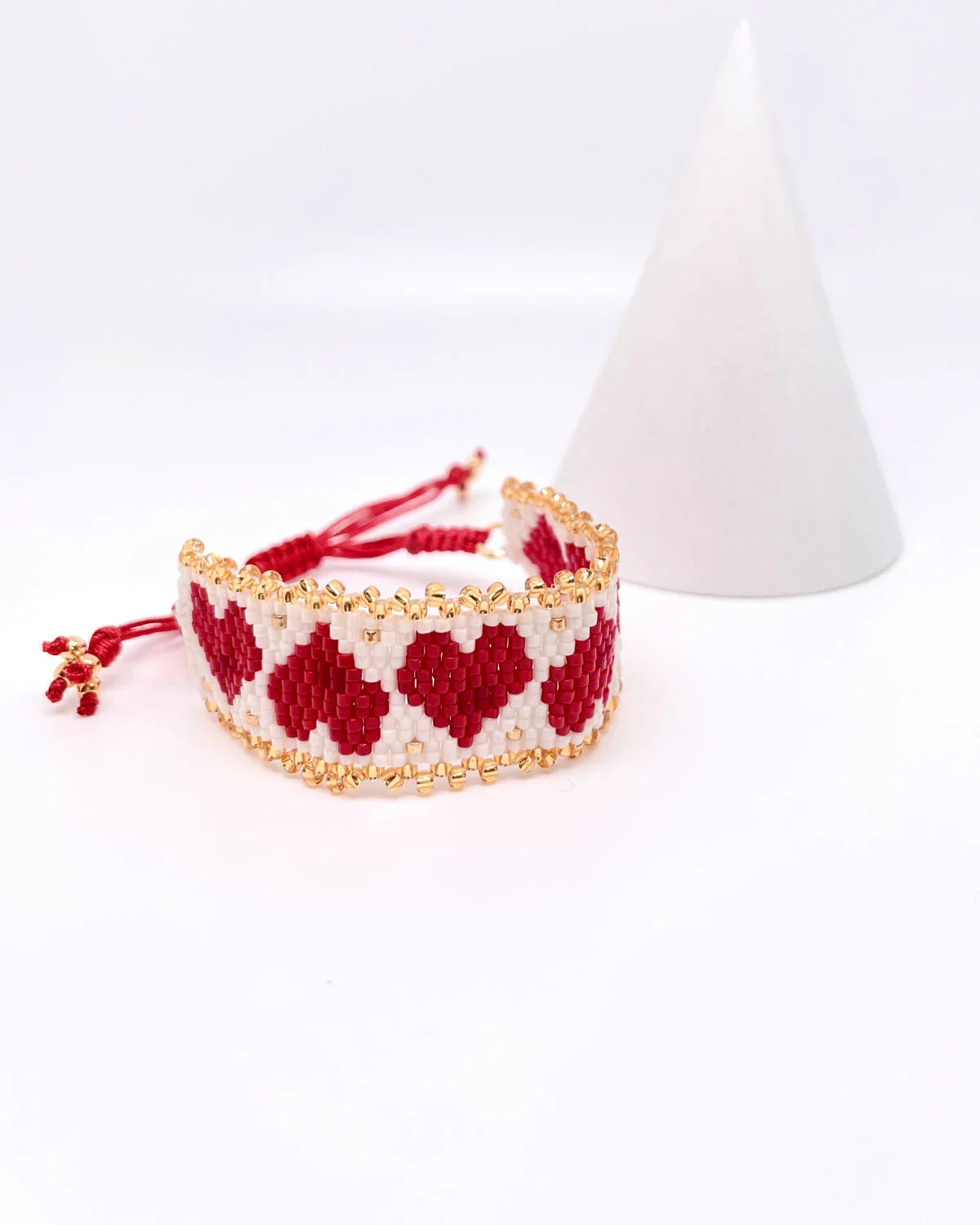Pulsera artesanal de corazones en rojo y blanco con detalles dorados de Erika Valencia