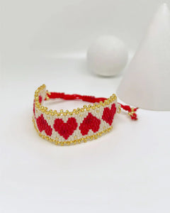 Pulsera artesanal de corazones rojos y blancos con detalles dorados hecha a mano por Erika Valencia