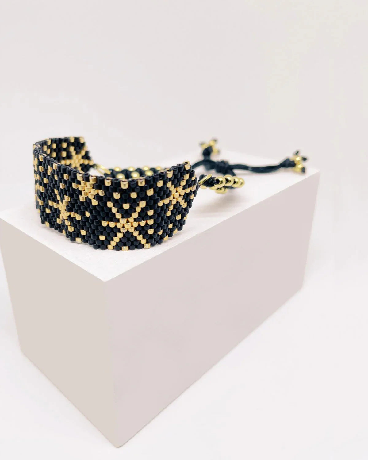 Pulsera artesanal de lujo negra y dorada con diseño tejido y cierre ajustable