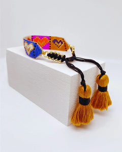 Pulsera artesanal hecha a mano con diseño de corazones y borlas amarillas de Erika Valencia