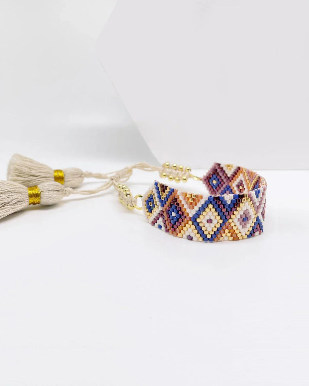 Pulsera rombos artesanal de cuentas en tonos beige, azul y marrón con borlas beige